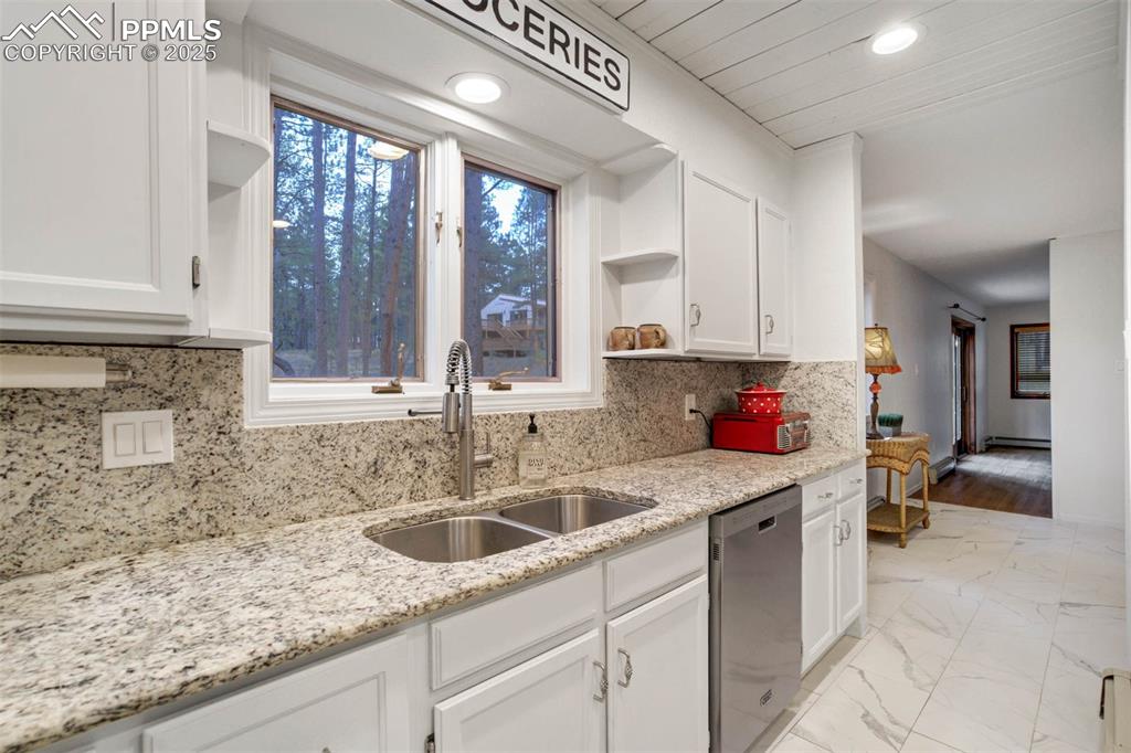 Kitchen with open shelves, tasteful backsplash, white cabinetry, light marble finish floors, and dishwasher