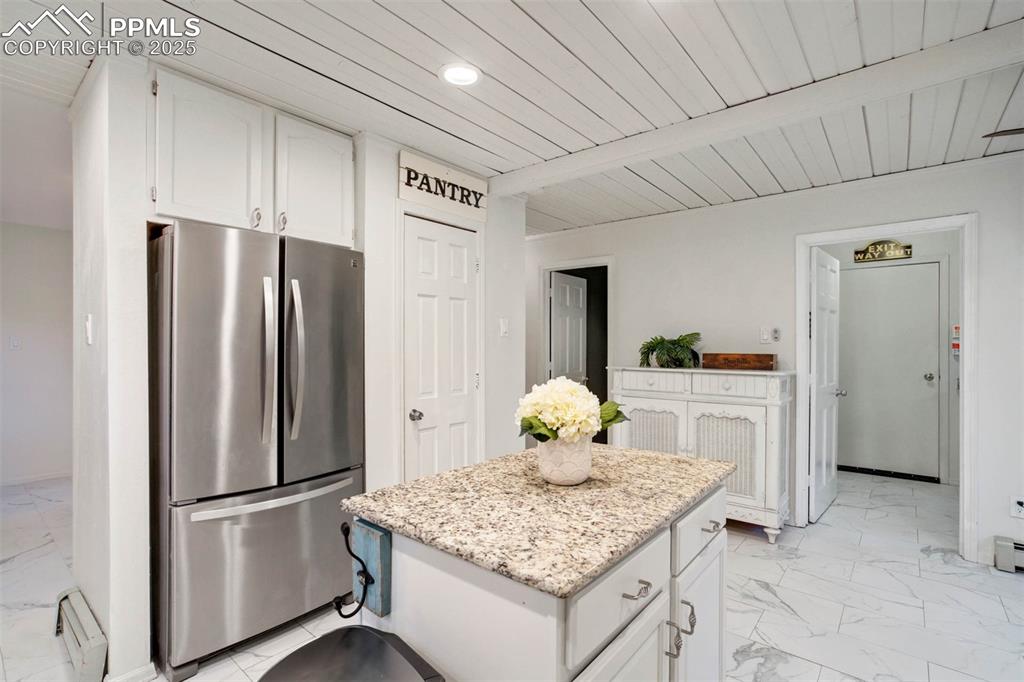 Kitchen with white cabinetry, freestanding refrigerator, light marble finish flooring, wood ceiling, and recessed lighting