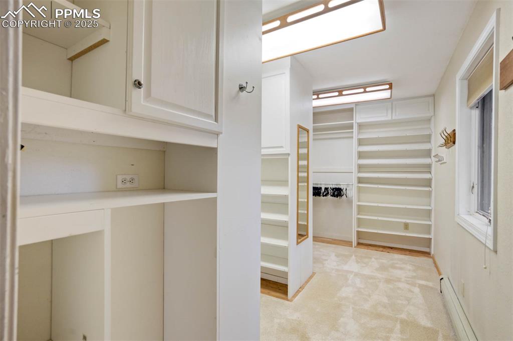 Walk in closet featuring baseboard heating and light colored carpet