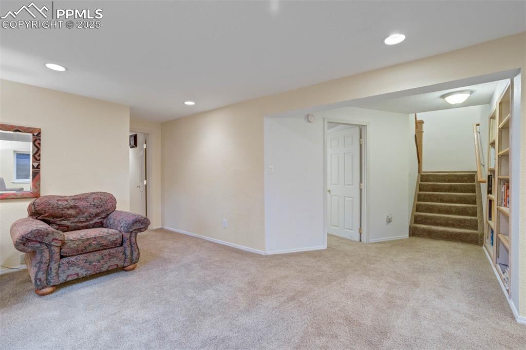 Sitting room featuring light colored carpet, recessed lighting, and stairs