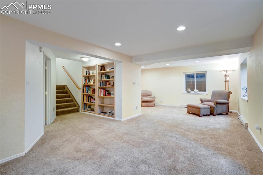 Living area with light colored carpet, recessed lighting, stairs, and a baseboard radiator