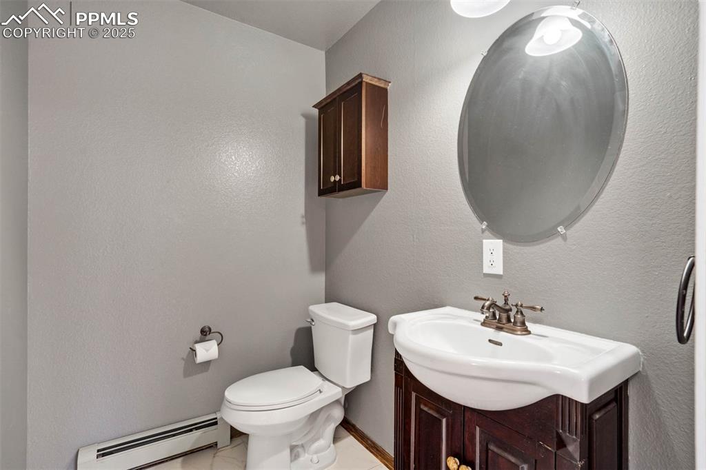 Half bathroom featuring a baseboard radiator, vanity, and a textured wall