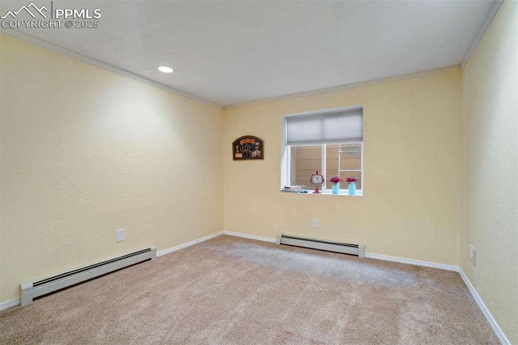 Empty room with a baseboard heating unit, ornamental molding, light colored carpet, recessed lighting, and a textured wall