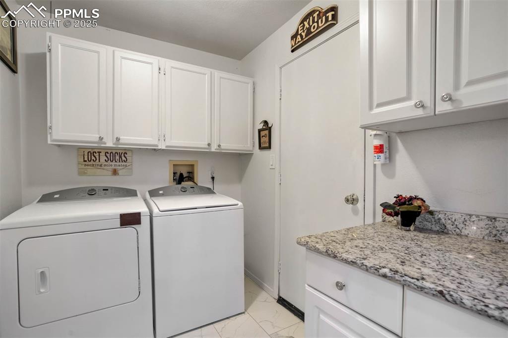 Washroom featuring cabinet space, light marble finish flooring, and separate washer and dryer