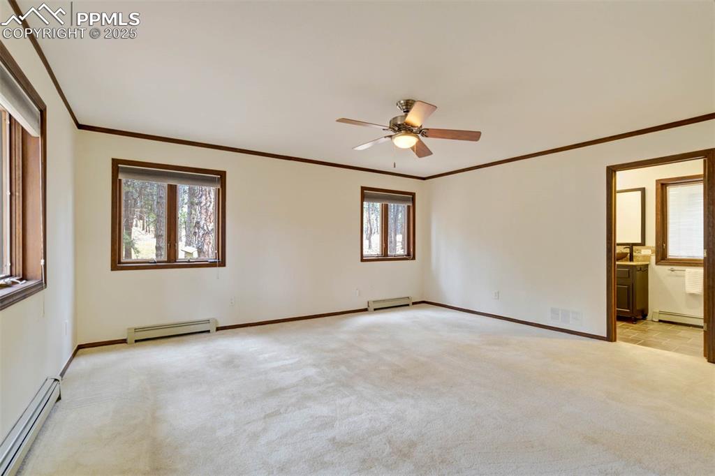 Unfurnished bedroom with a baseboard heating unit, crown molding, light colored carpet, and ceiling fan