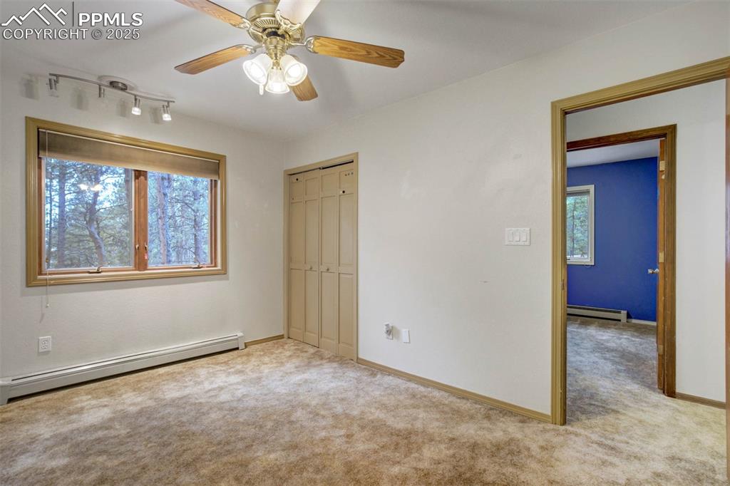 Unfurnished bedroom with a baseboard heating unit, light colored carpet, a ceiling fan, and a closet