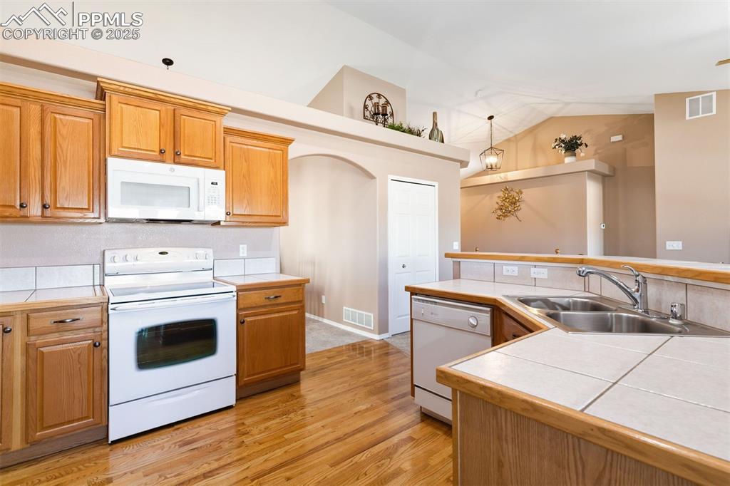 Bright, clean kitchen with vaulted ceiling and open to living room.