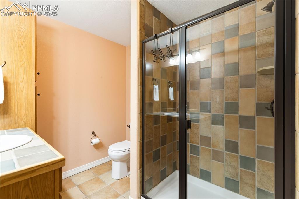 Warm tones extend to lower Level bathroom with tiled shower and floors. 