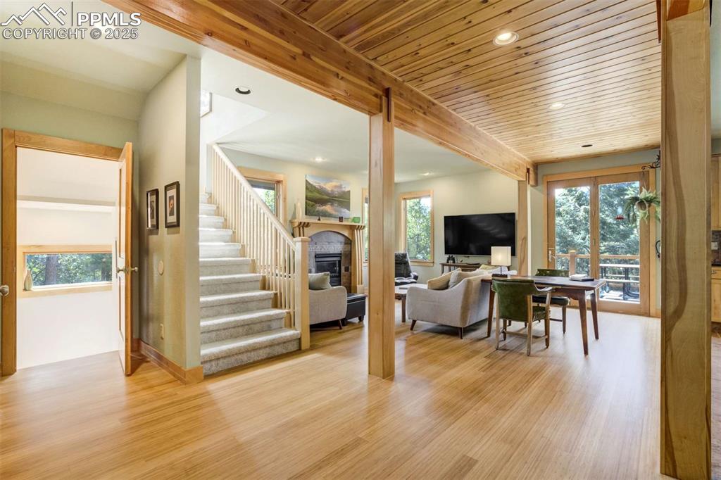 Living room with recessed lighting, bamboo flooring, a fireplace, stairway, and wood ceiling.  Lots of extra detail in the artistic wood designs.
