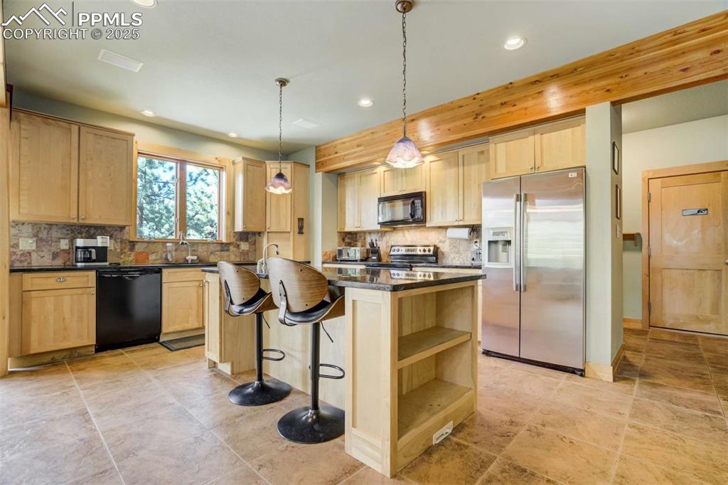 Kitchen featuring black appliances, a kitchen island, a breakfast bar, and tasteful backsplash