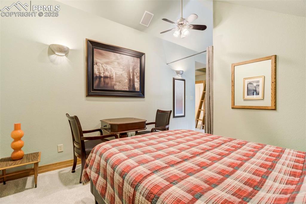 Bedroom with vaulted ceiling, light carpet, and ceiling fan