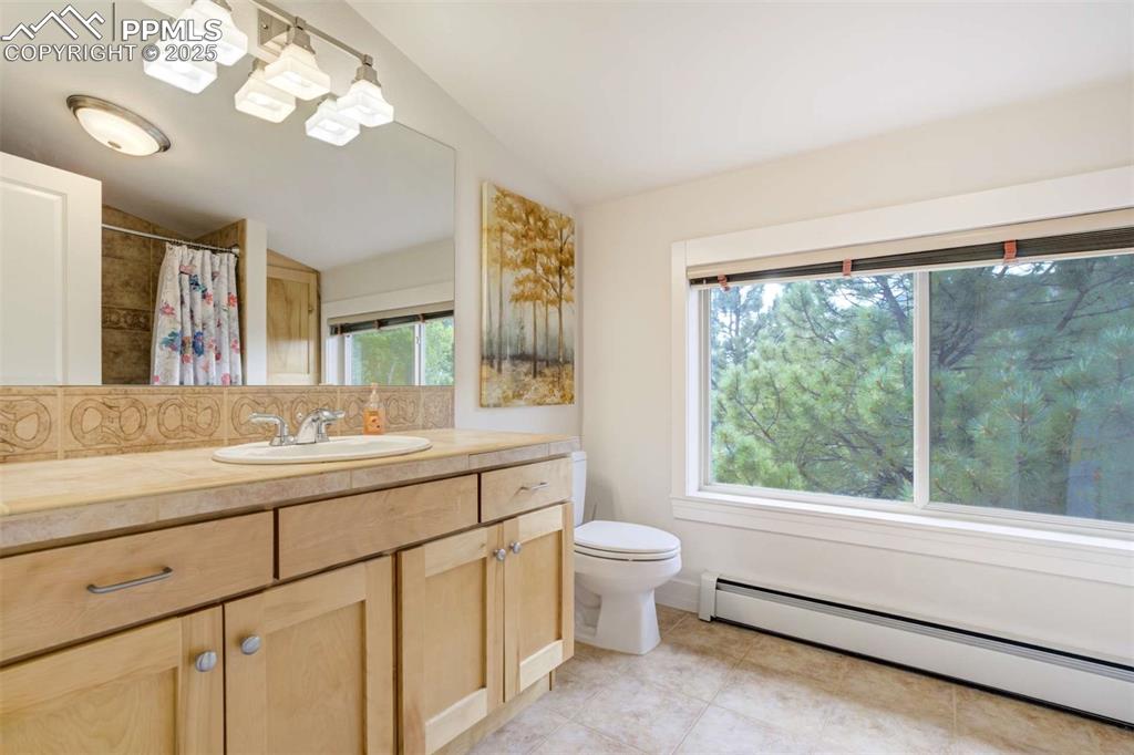 2nd guest bathroom featuring a baseboard radiator, lofted ceiling, vanity, tile patterned floors