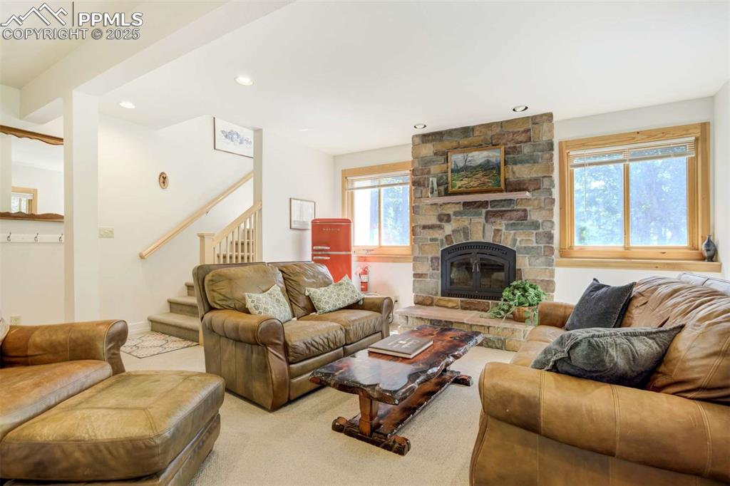 Living room featuring stairs, carpet flooring, recessed lighting, and a fireplace