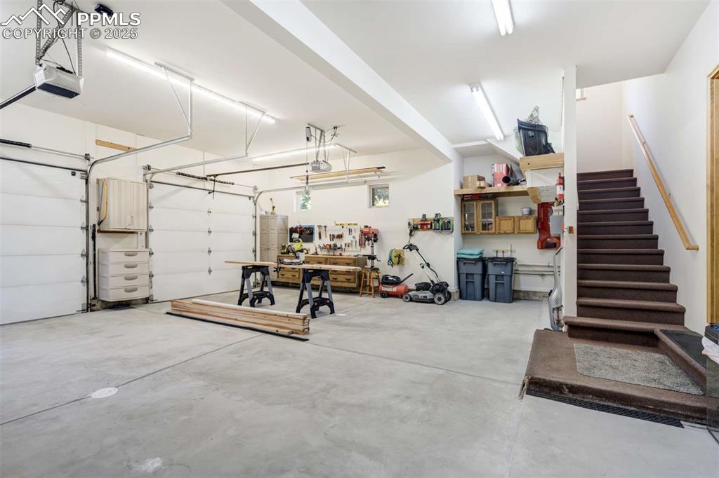 Garage with a workshop area and a garage door opener.  Also shows stairs to private entrance to guest suite.
