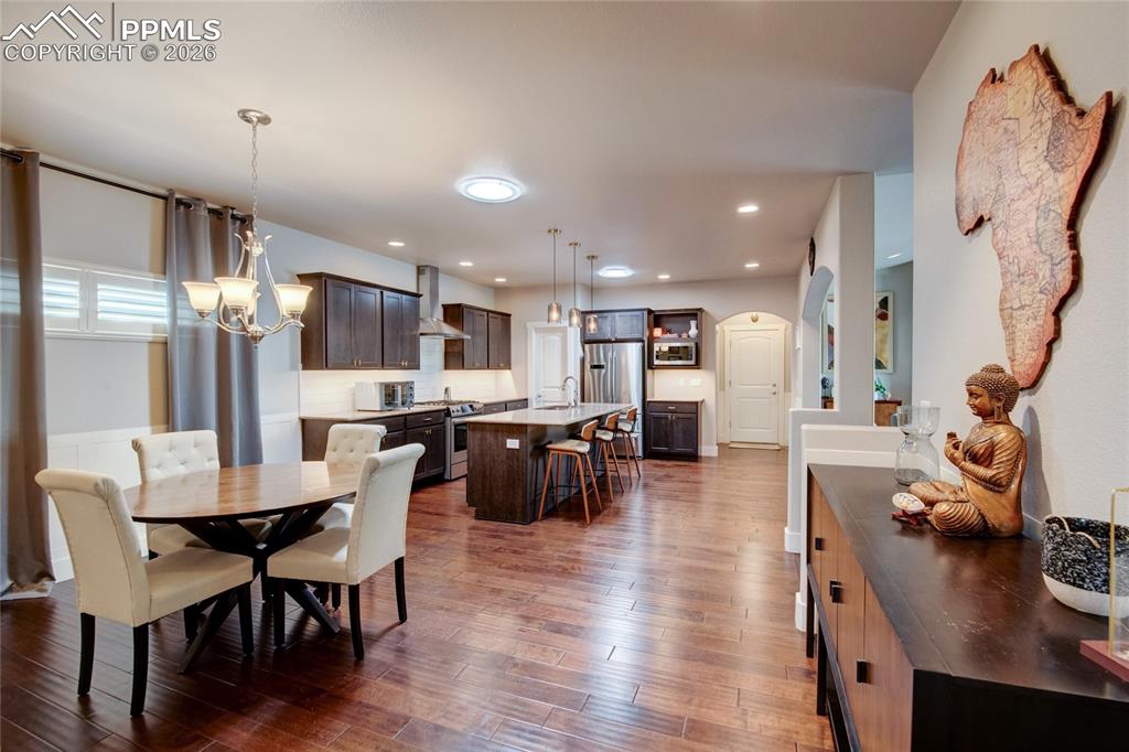 Dining room with a chandelier, dark wood finished floors, and recessed lighting