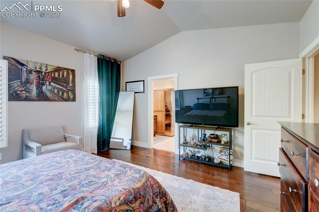 Bedroom featuring lofted ceiling, dark wood finished floors, ceiling fan, and connected bathroom
