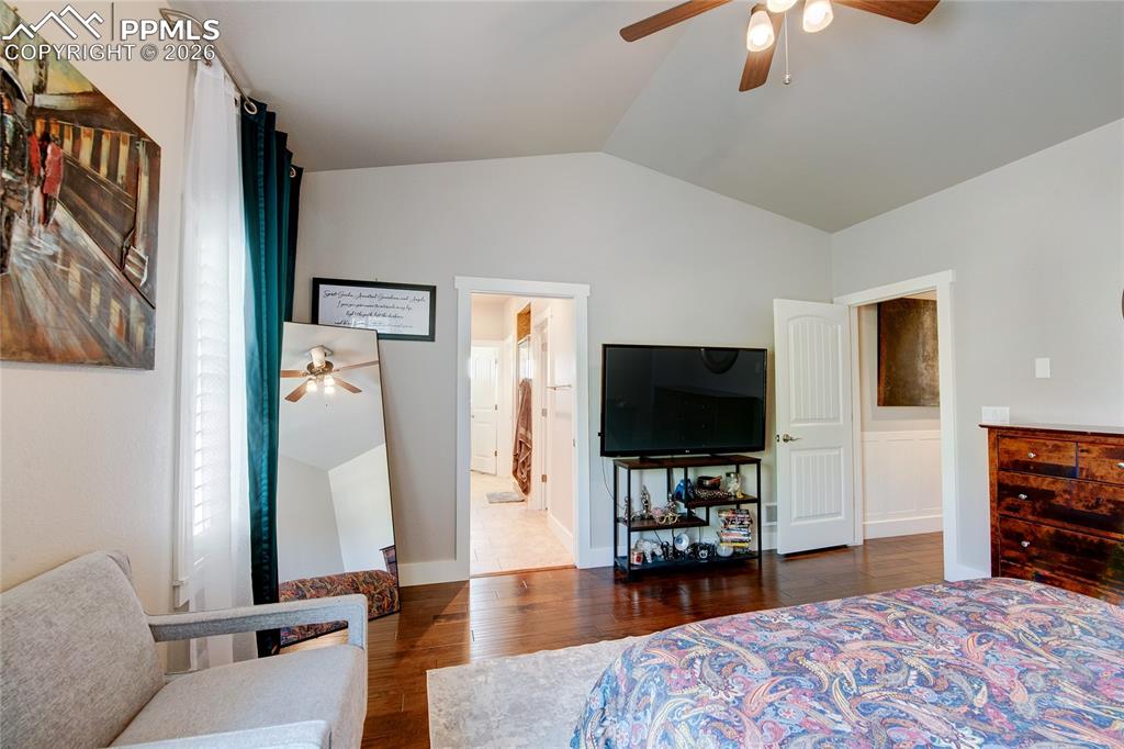 Bedroom featuring lofted ceiling, dark wood-style floors, ceiling fan, and ensuite bath