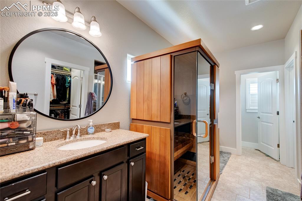 Bathroom with a sauna, vanity, light tile patterned floors, a spacious closet, and recessed lighting
