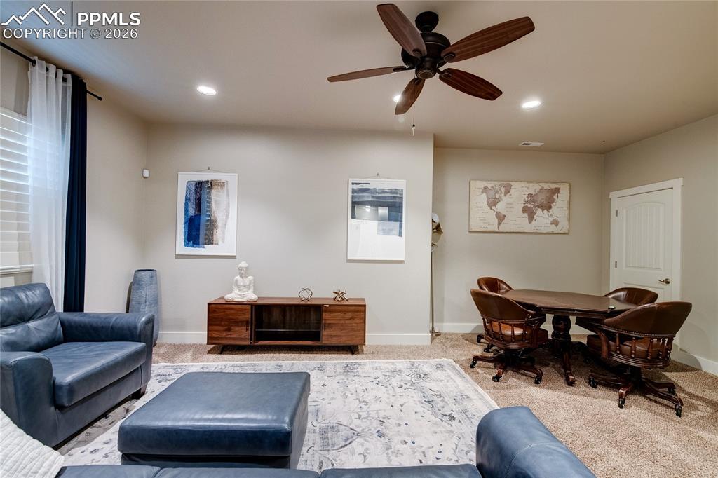 Carpeted living area with ceiling fan and recessed lighting