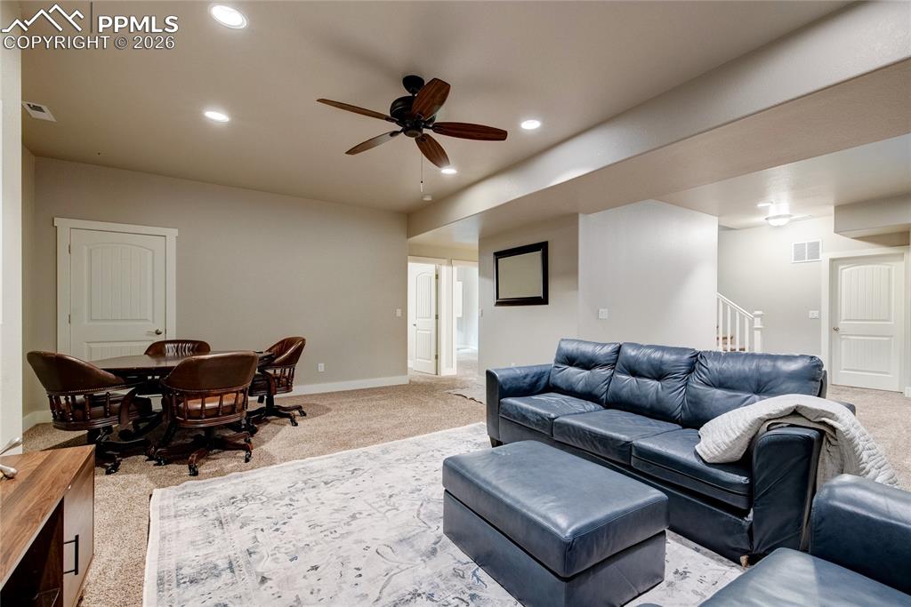 Living room with carpet, recessed lighting, ceiling fan, and stairway