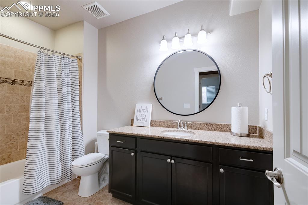 Bathroom featuring shower / bath combo with shower curtain, vanity, and light tile patterned floors