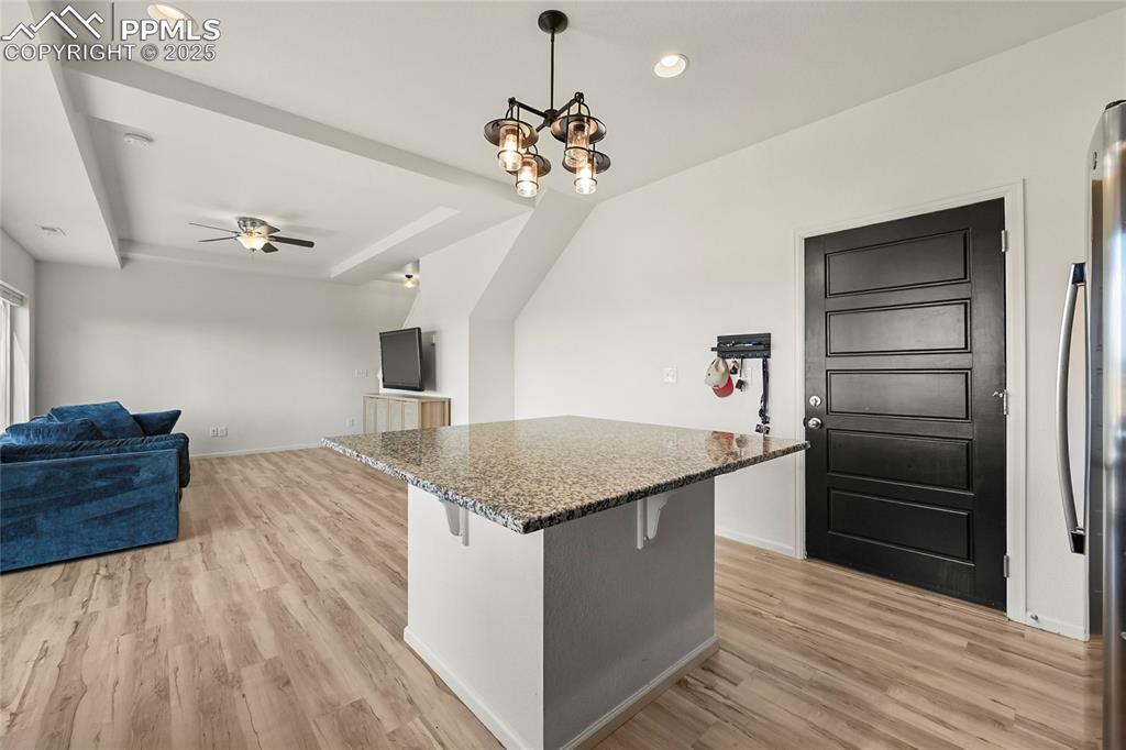 Kitchen featuring a kitchen bar, decorative light fixtures, dark stone countertops, light wood-style flooring, and recessed lighting