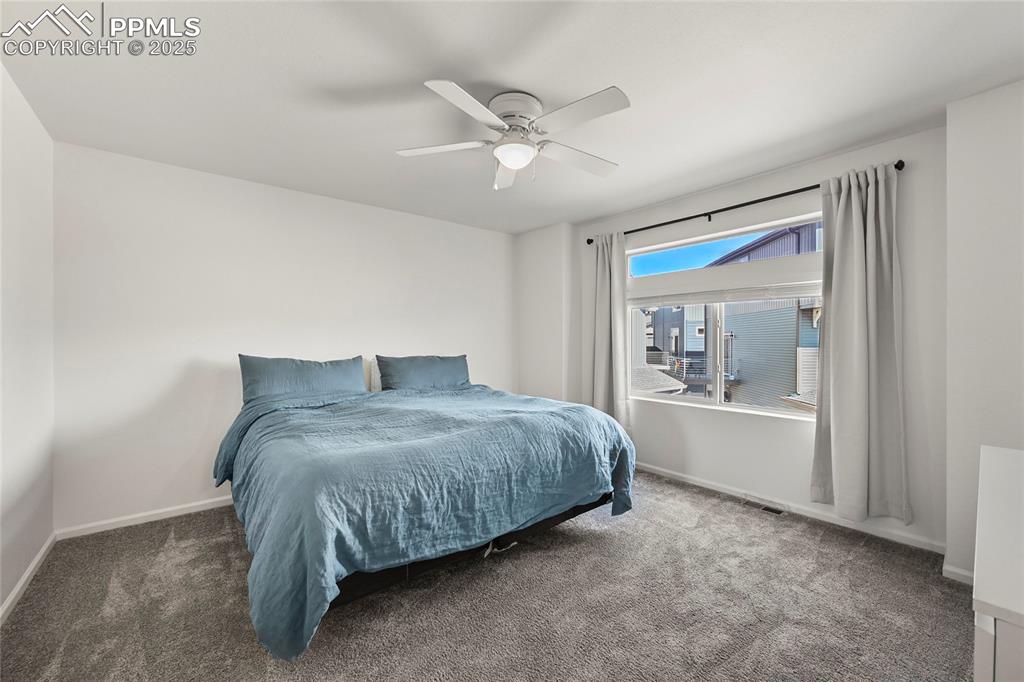 Carpeted bedroom with baseboards and a ceiling fan
