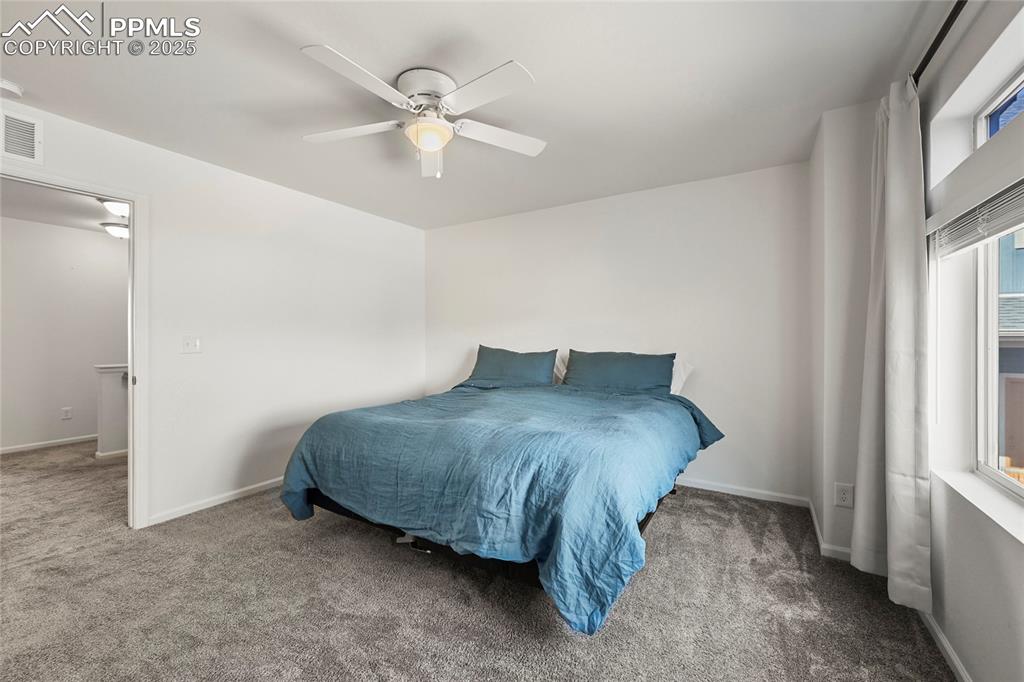 Carpeted bedroom with ceiling fan and baseboards