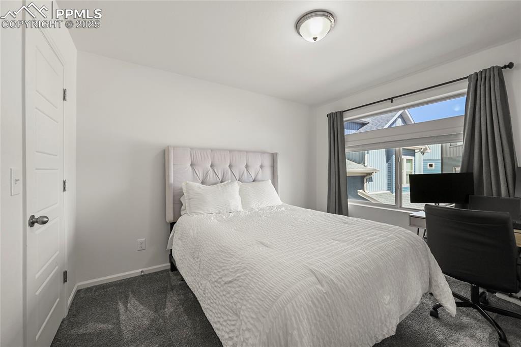 Bedroom with dark carpet and a desk