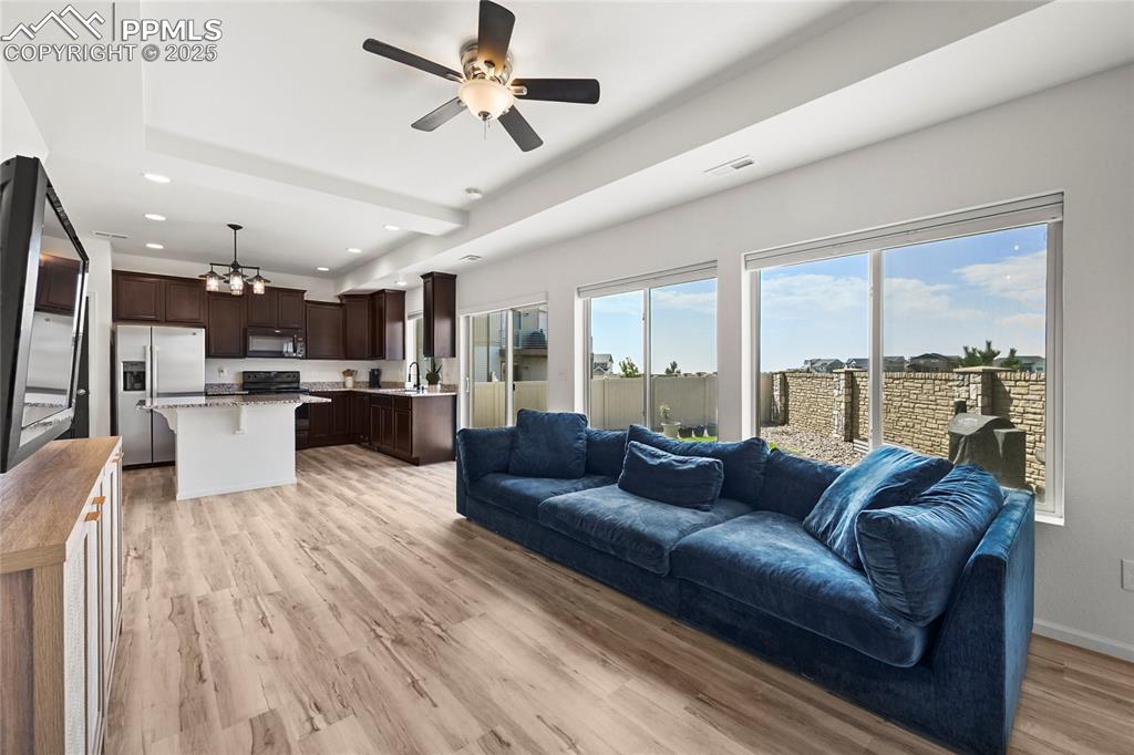 Living room with a ceiling fan, light wood-style flooring, and recessed lighting