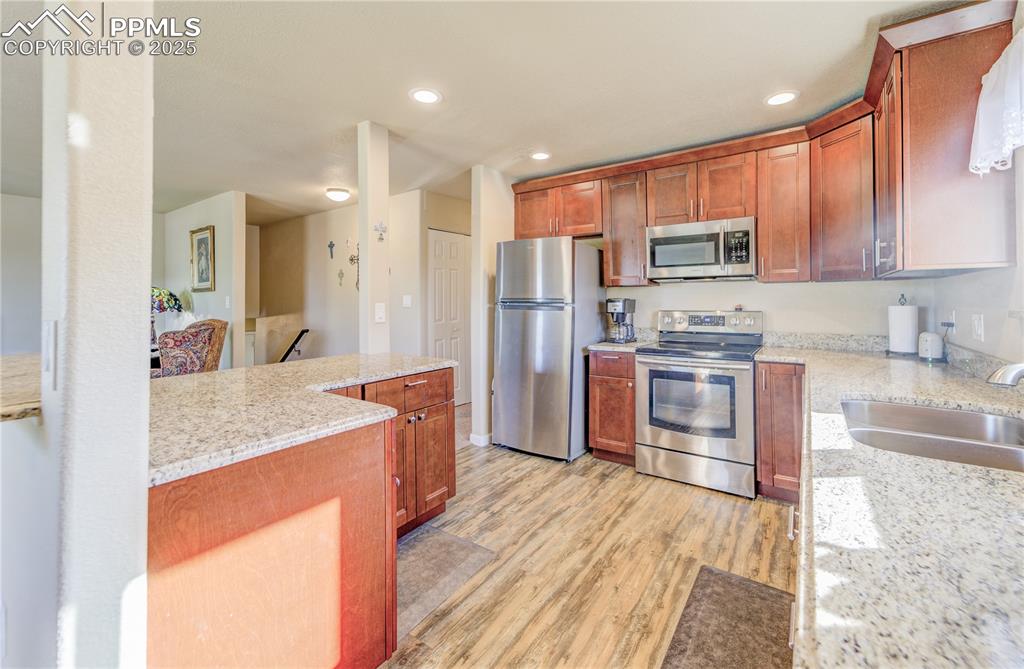 Kitchen featuring light stone counters, stainless steel appliances, lots of natural light