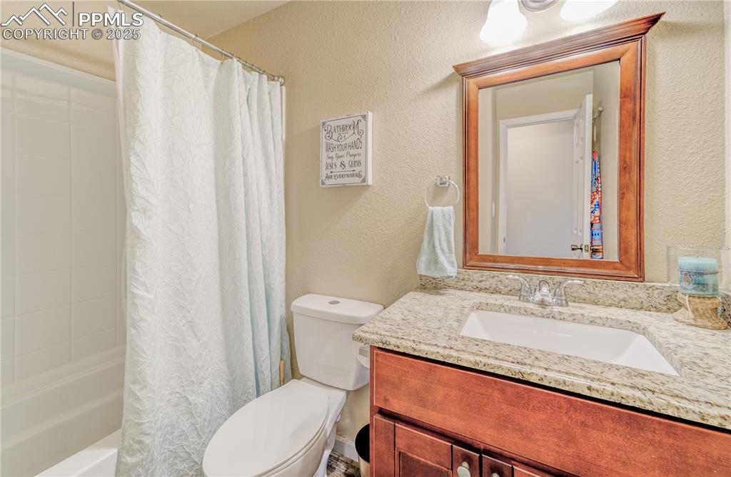 Full bathroom with vanity, shower / tub combo, and toilet