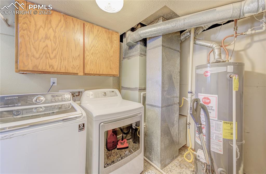 Laundry area featuring cabinets, gas water heater, independent washer and dryer, and a textured ceiling