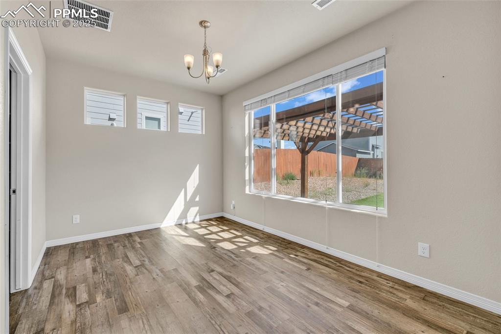 Unfurnished dining area with wood finished floors and a chandelier
