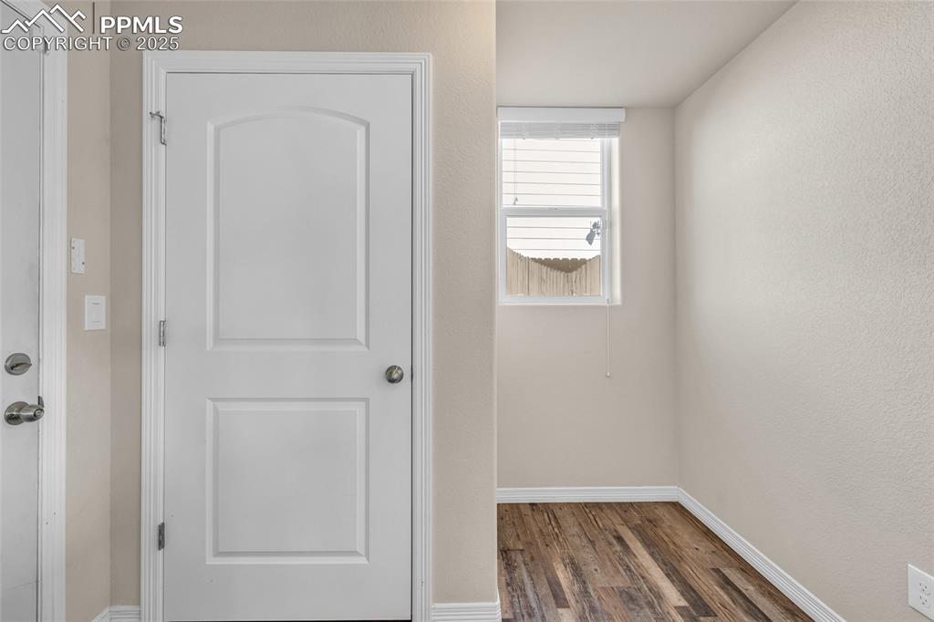 Hall with dark wood-type flooring and a textured wall