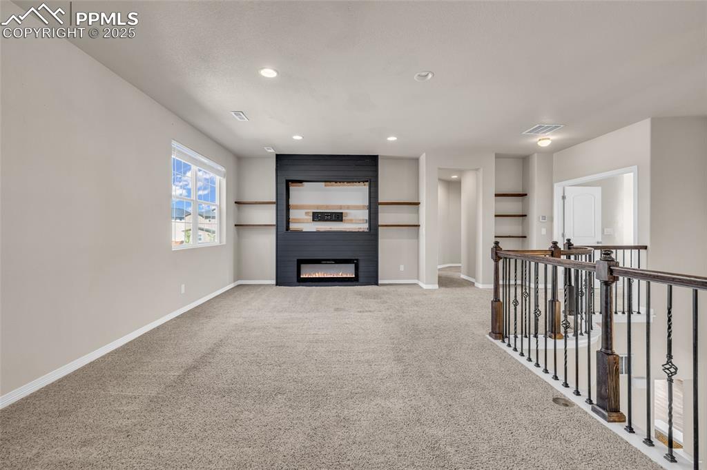 Unfurnished living room featuring carpet floors, a fireplace, and recessed lighting