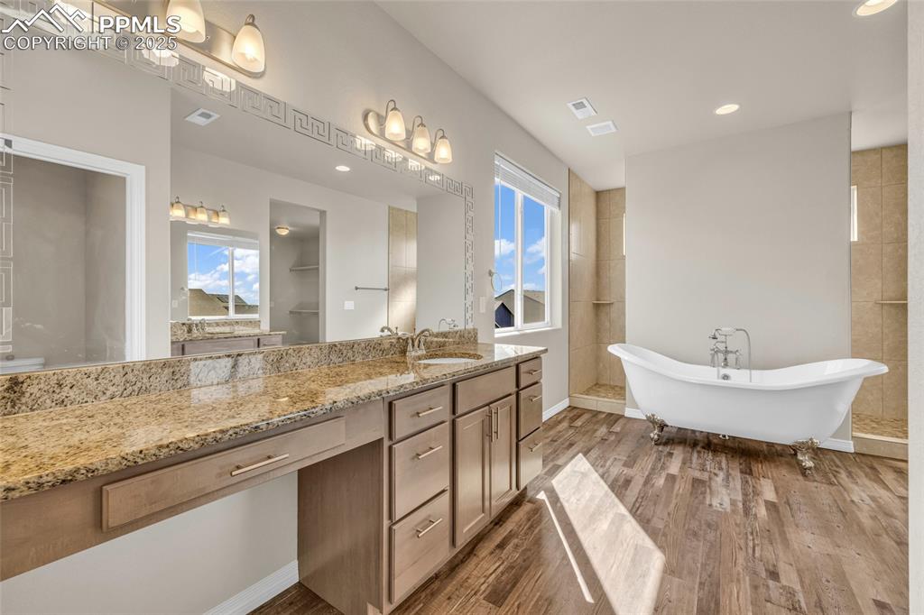 Full bath featuring vanity, a freestanding bath, dark wood-type flooring, and recessed lighting