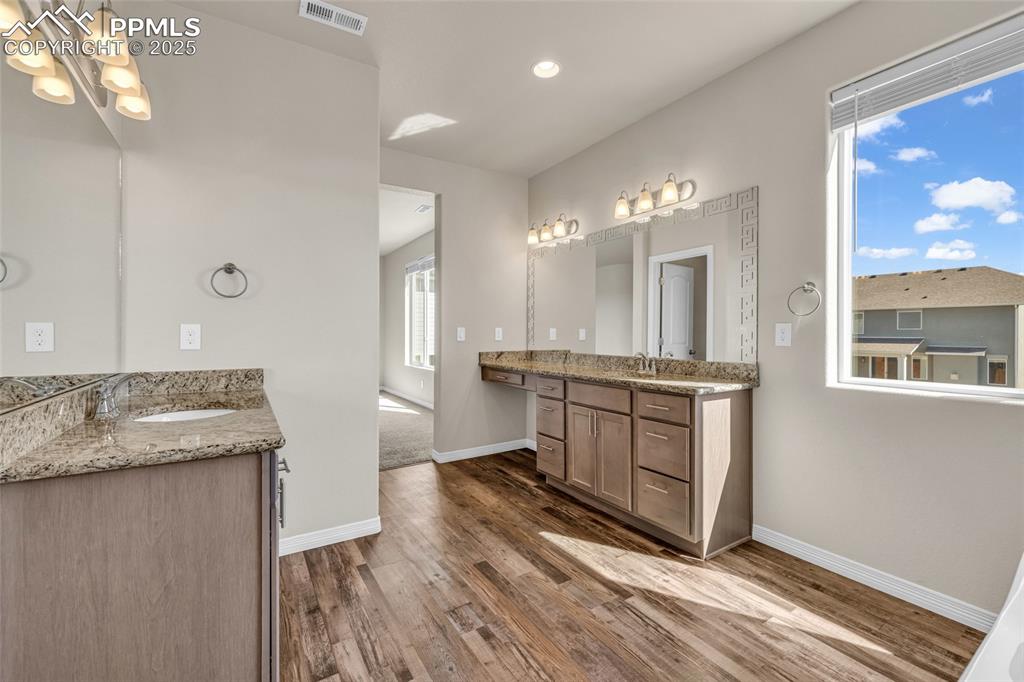 Bathroom with two vanities, dark wood-style floors, and recessed lighting