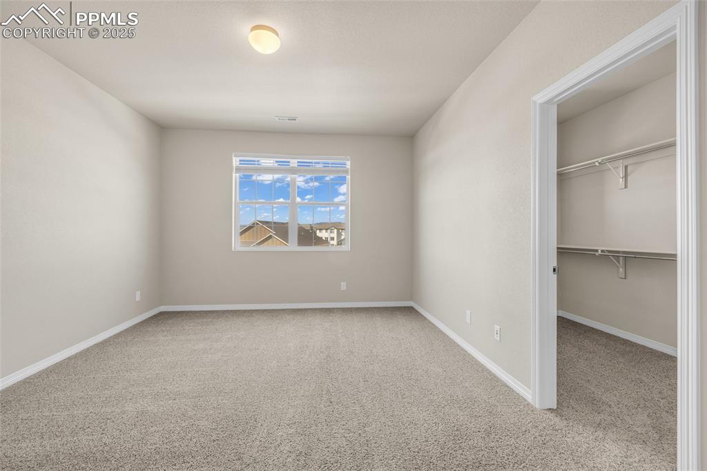 Unfurnished bedroom with light carpet and a spacious closet
