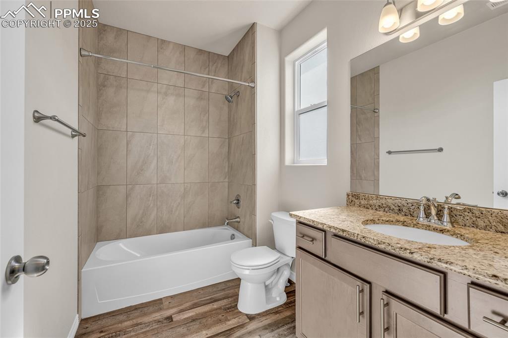 Bathroom featuring tub / shower combination, vanity, and light wood-style floors