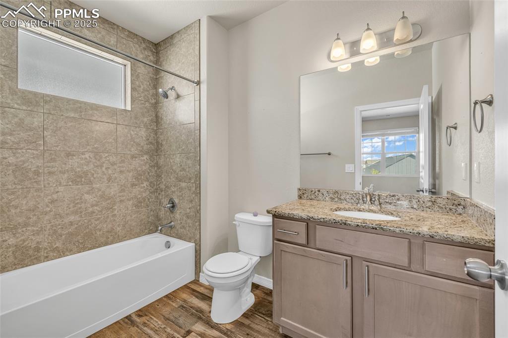 Full bathroom featuring healthy amount of natural light, shower / bathtub combination, dark wood-style floors, and vanity