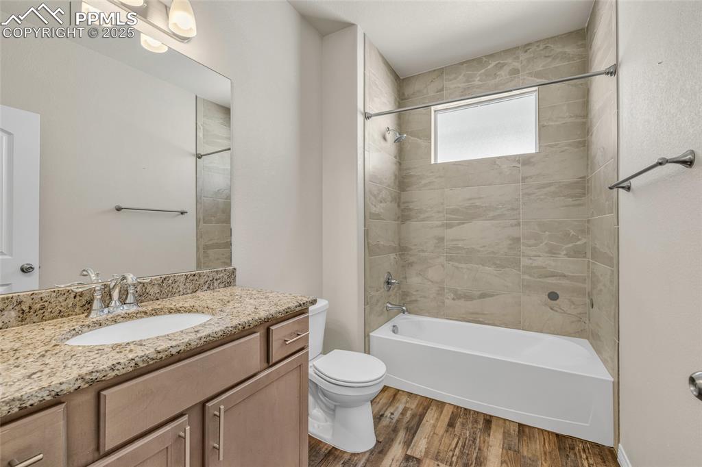 Full bath with shower / washtub combination, vanity, and dark wood-style floors