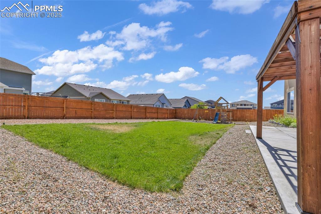 Fenced backyard featuring a residential view, a playground, and a patio