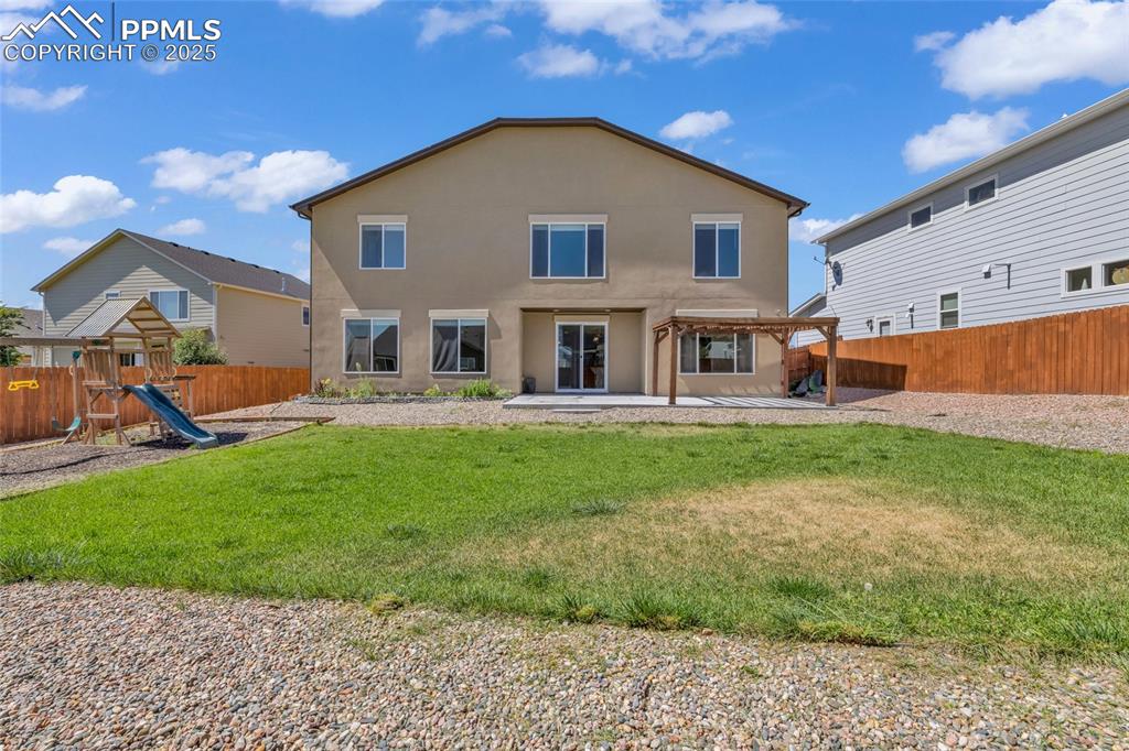 Back of property with a patio area, a playground, a fenced backyard, and stucco siding