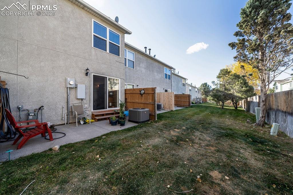 Backyard area with concrete patio and green space with mature trees.