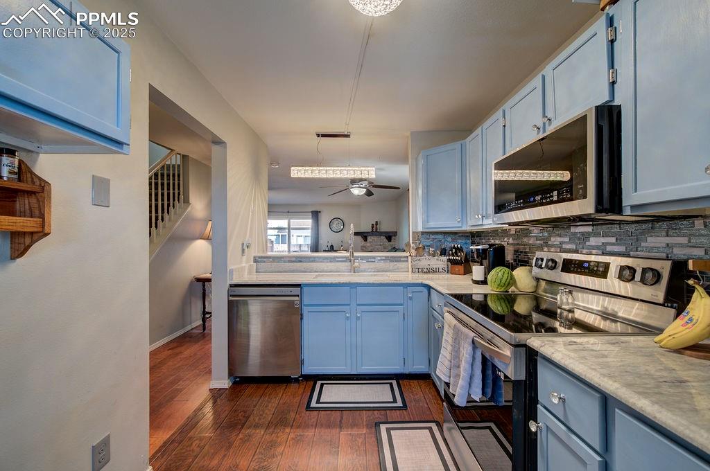 The Kitchen overlooks the Dining Area and Living Room with wood laminate floors, painted wood cabinets, and ample counterspace for easy food preparation.