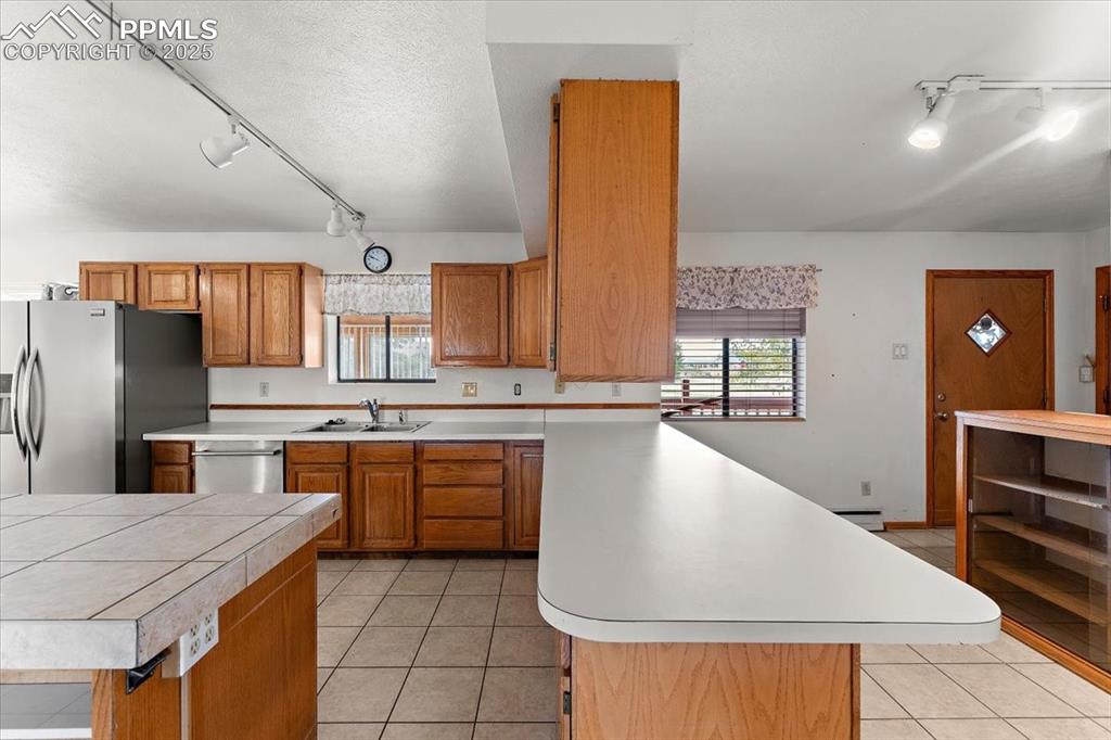 Kitchen featuring track lighting, light tile patterned flooring, brown cabinetry, and a textured ceiling