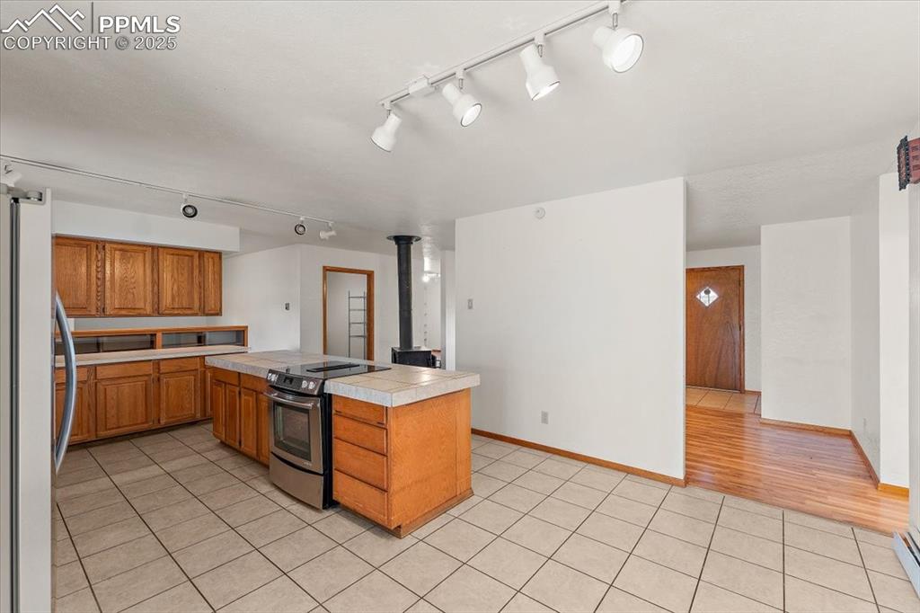 Kitchen featuring stainless steel appliances, light tile patterned flooring, track lighting, and brown cabinets
