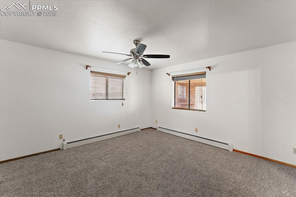 Spare room with baseboard heating, carpet, and a ceiling fan