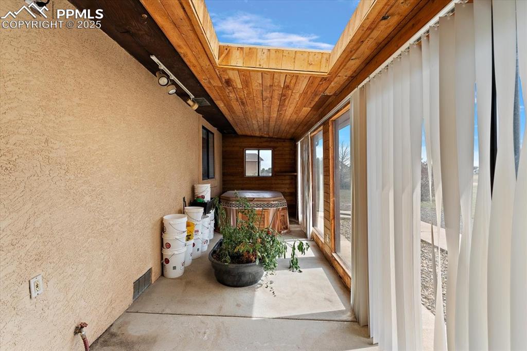 Sunroom / solarium with a textured wall, wood ceiling, a skylight, and concrete floors